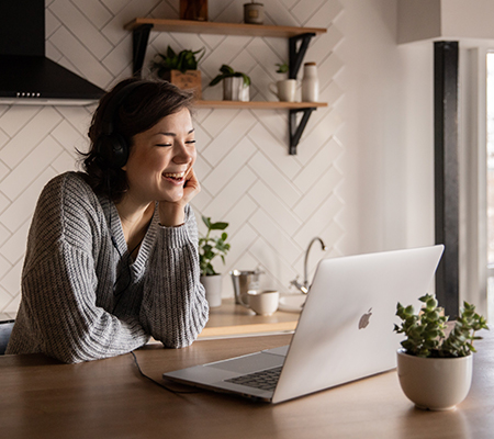 girl laughing, looking at open laptop on clean kitchen counter. potted succulent